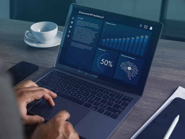 Hands operating a laptop with an analytics dashboard of charts and graphs